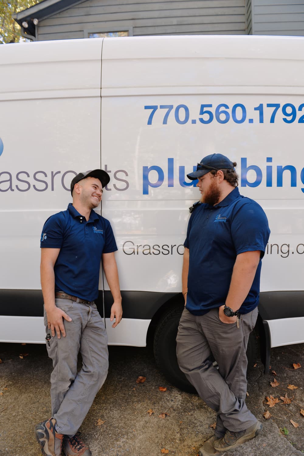 two plumbers in front of a work truck