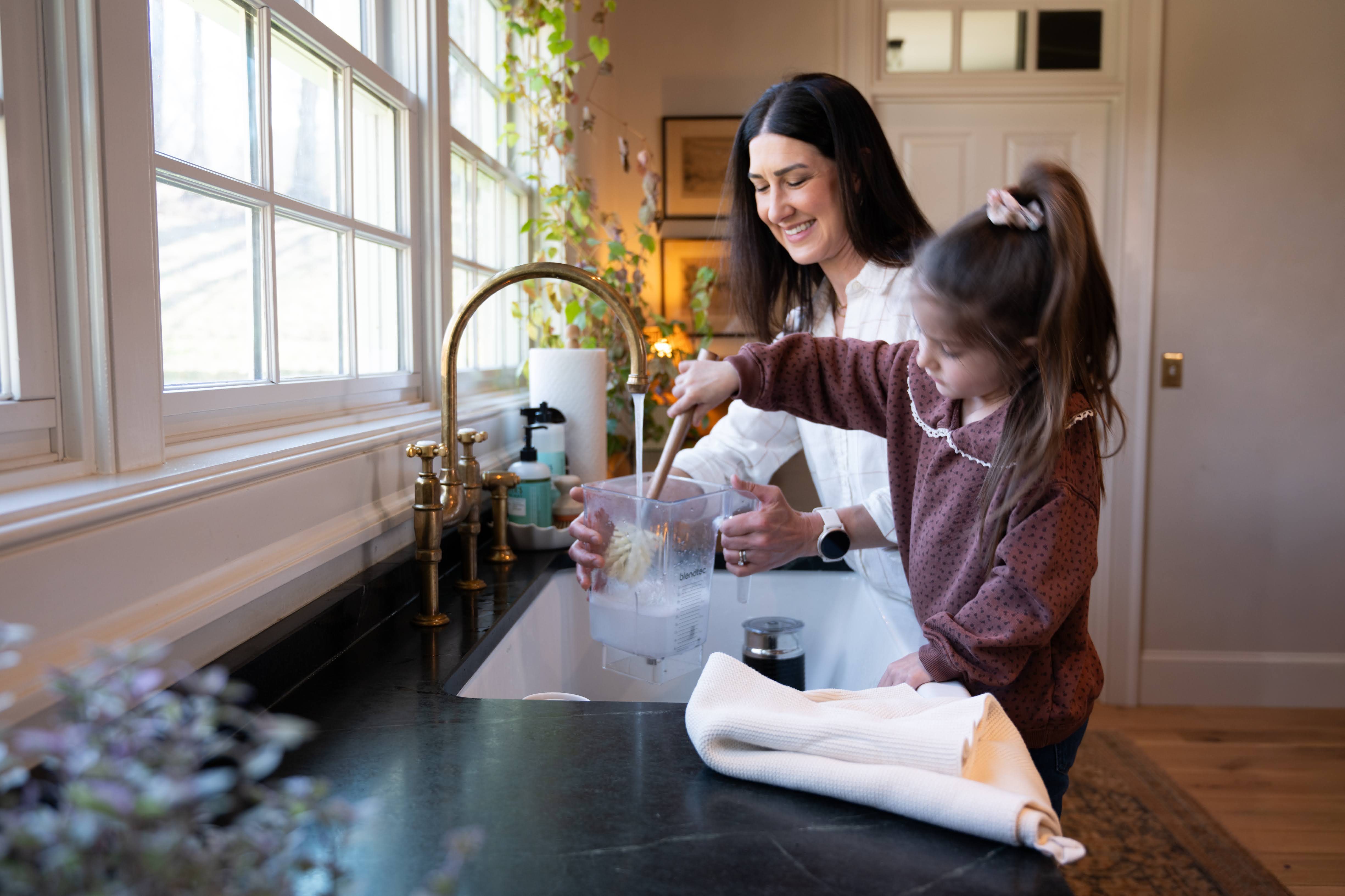 Woman and daughter washing dishes at the sink. 